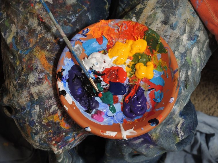لوحة ألوان مليئة بألوان زاهية وفرشاة في مرسم الفنون